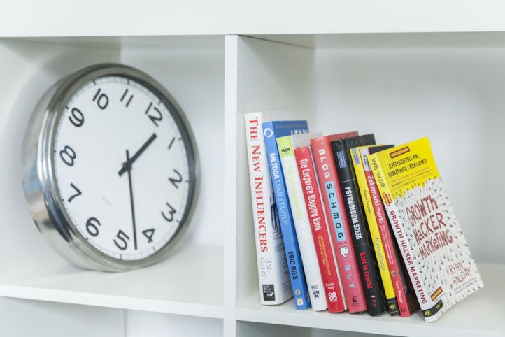 Zegar i książki stojące w szafce